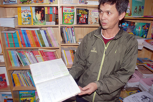 Chủ Nhà sách Chí Thành với cuốn sổ đăng ký của hàng trăm phụ huynh đặt mua sách VNEN.