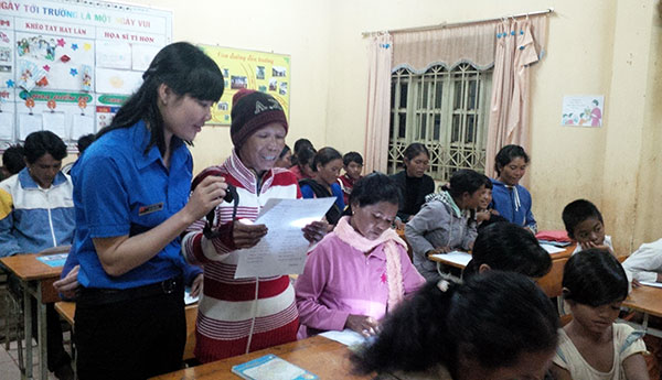Cô giáo trẻ Đàm Thị Hồng đang soi đèn giúp bà Ka Ớt đọc chữ