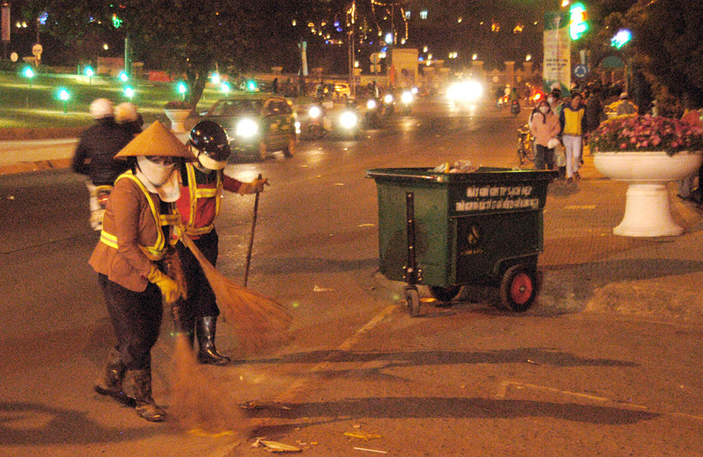  Khi thành phố lên đèn, các chị công nhân Đội Môi trường đô thị cần mẫn làm việc để cho thành phố sạch, đẹp hơn. Ảnh: Mai Văn Bảo