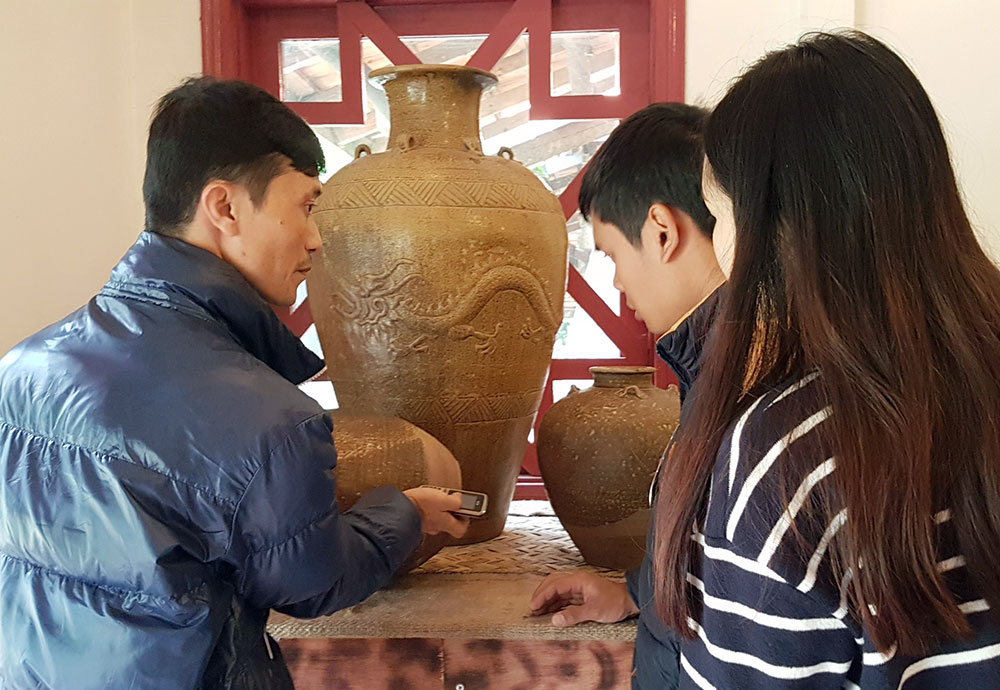 Nguyễn Quốc Dũng giới thiệu nét đặc sắc của gốm cổ đến du khách. Ảnh: T.Vân