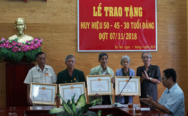Ông Trương Thái Anh Quốc,  Phó Bí thư Huyện ủy Đạ Tẻh (bìa phải), trao huy hiệu Đảng cho các đảng viên