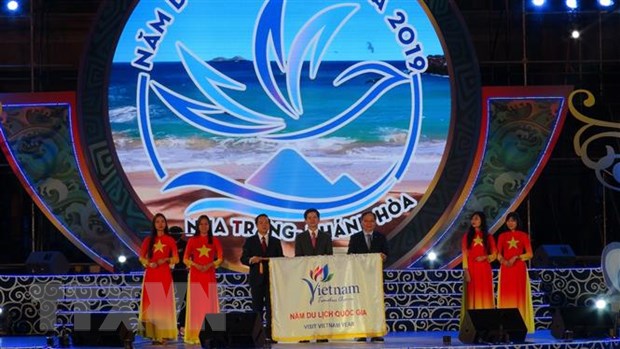Thứ trưởng Bộ Văn hóa, Thể thao và Du lịch ( giữa) và Lãnh đạo Ủy ban Nhân dân tỉnh Khánh Hòa (phải) trao cờ đăng cai Năm Du lịch quốc gia 2020 cho tỉnh Ninh Bình (bên trái)