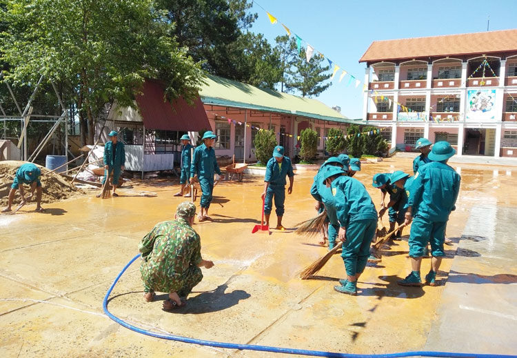 Các chiến sĩ dân quân giúp Trường Mầm non Đạ Nhim dọn dẹp bùn đất 