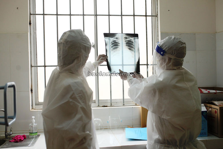 Bác sĩ Đỗ Văn Chiến cùng cộng sự là điều dưỡng Phan Bảo Quốc trong bộ đồ bảo hộ kín bưng, đang xem xét X-Quang phổi của bệnh nhân 