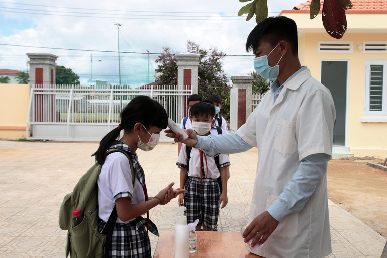 Học sinh Trường Tiểu học Võ Thị Sáu được đo thân nhiệt, rửa tay sát khuẩn trước khi vào lớp